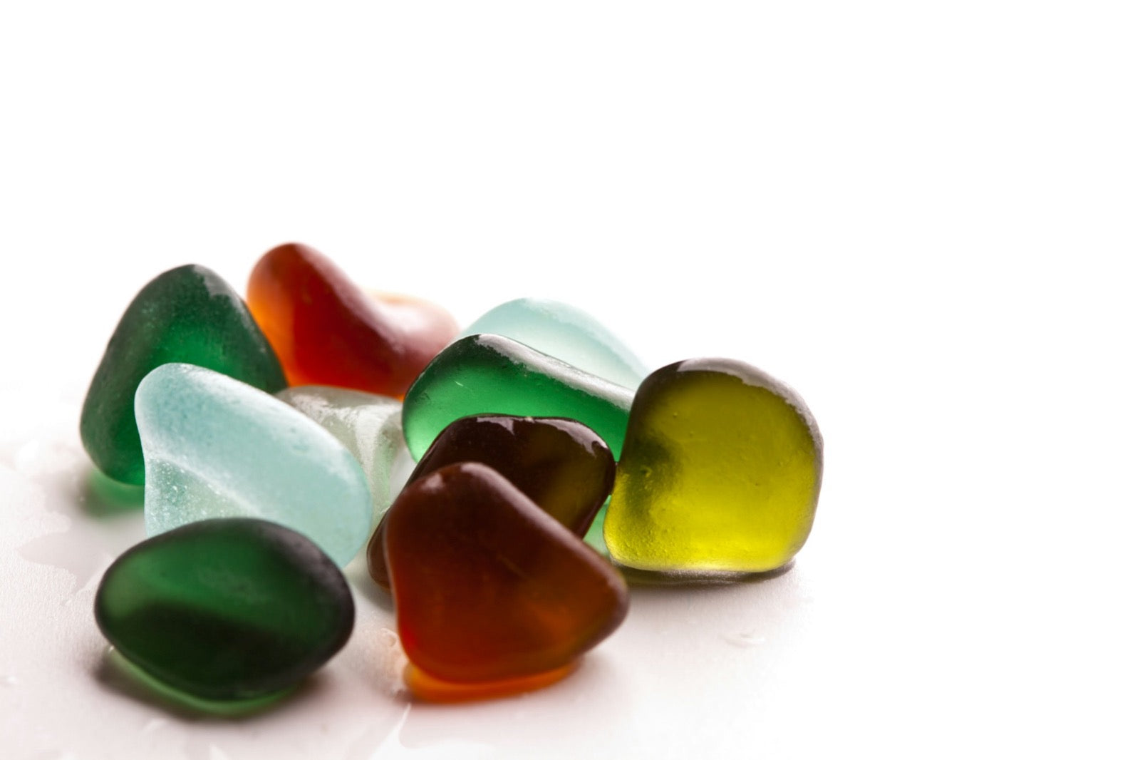 Mixed coloured gem rough on a white ground